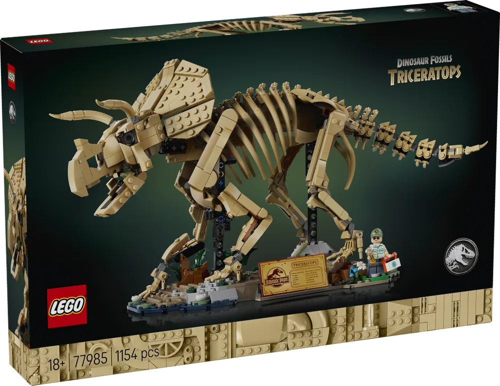 Front view of the LEGO Dinosaur Fossils: Triceratops 77985 box, showing the tan brick-built skeleton on a base with a minifigure and a display plaque. The box art is dark green with 'Dinosaur Fossils Triceratops' and 'LEGO Jurassic Park' branding.