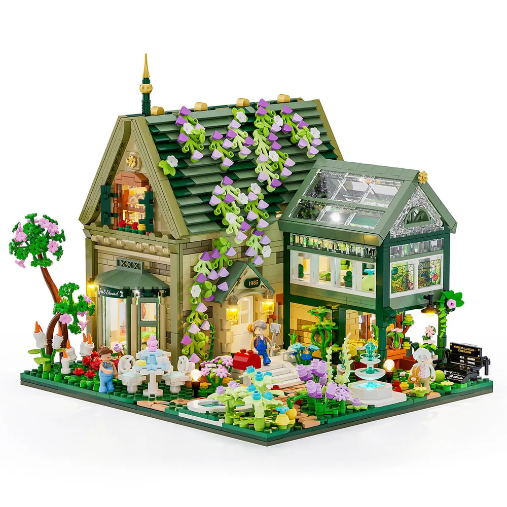A detailed brick-built house with a green roof covered in purple and white wisteria, next to a matching greenhouse. The house and garden are brightly lit, showcasing architectural details and lush plant life with minifigures.
