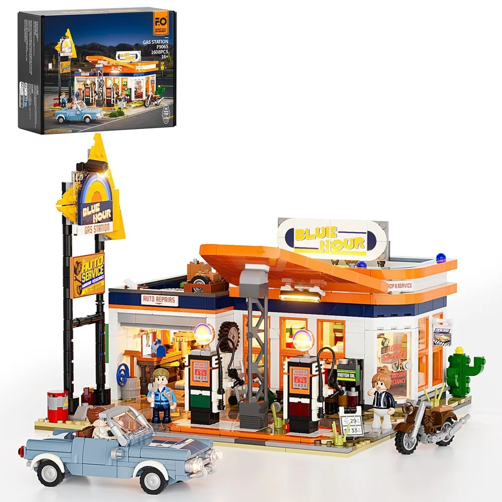 A wide shot of the Lumibricks F9065 gas station set in daylight, showing its orange and blue building, prominent 'BLUE HOUR' sign, gas pumps, a blue convertible car, a motorcycle, and several minifigures. The set box is visible in the top left.