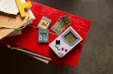 Game Boy display on red desk.