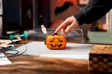 Hand pressing pumpkin stem, activating light.