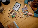 Child's hands building LEGO Privet Drive.