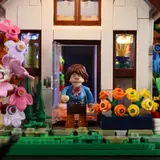Close-up of minifigure at illuminated greenhouse entrance.