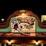 Close-up of the lit 'Cowgirls Show' sign.