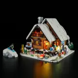 Illuminated Lumibricks Ski Lodge F9041 at night with glowing fire pit.