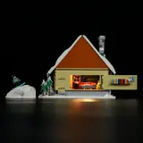 Ski Lodge with hinged wall open, illuminated interior, and snowboarder.